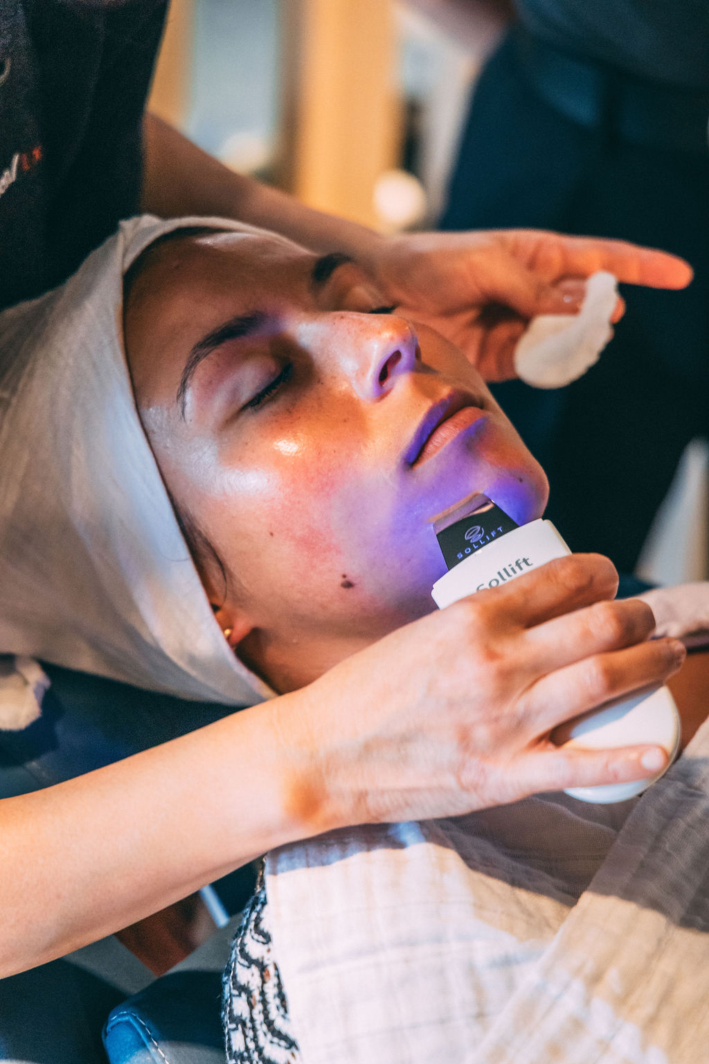An upright FaceSpace facial chair in the open salon, washed in cobalt light.